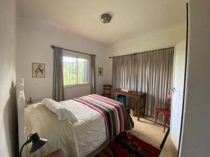 a bedroom with a bed and a window and a desk at Casa Margaret - Hermosa vista a la Sierra in La Cumbre