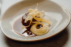 a white plate with a chocolate doughnut with icing at The Dunes in Tenby