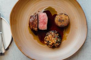 a plate of food with meat and sauce on a table at The Dunes in Tenby