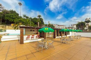 un patio con mesas, sillas y sombrillas verdes en Hotel Golden Park Rio de Janeiro Aeroporto en Río de Janeiro
