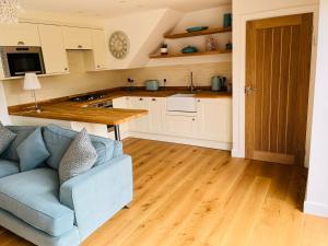 a living room with a blue couch and a kitchen at The Hayloft in Hernehill