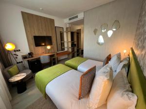 Habitación de hotel con 2 camas y sala de estar. en Hotel Ben Batouta - Tanger en Tánger