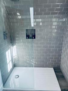 a bathroom with a shower with a white brick wall at The Hayloft in Hernhill