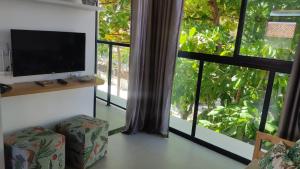 uma sala de estar com televisão e uma grande janela em Flat Macaraípe - Maraca Beach I em Porto de Galinhas