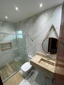 y baño con aseo, lavabo y espejo. en Brisa dos Anjos Suítes en Arraial do Cabo