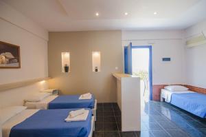 um quarto de hotel com duas camas com lençóis azuis em Skala Sunset Hotel and spa em Ios Chora
