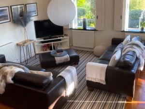 a living room with leather couches and a television at Tre Mynach Barmouth in Barmouth