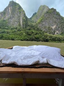 uma cama num barco com montanhas ao fundo em Nongkhiaw The Float House em Nongkhiaw