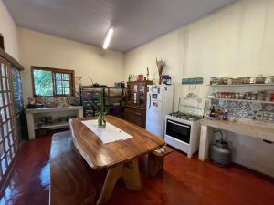 cocina con mesa de madera y nevera blanca en Vila Amor - Charmosa e Central, en Alto Paraíso de Goiás