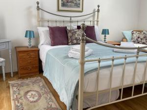 um quarto com uma cama de metal com almofadas roxas em Cottages at Woodlands, Grooms Cottage em Wareham