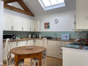 cocina con mesa, sillas y fregadero en Cottages at Woodlands, Grooms Cottage en Wareham