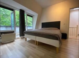 een slaapkamer met een bed en een groot raam bij Nette maisonnette in groene rustige wijk in Rijswijk
