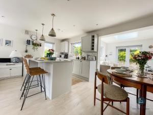 a kitchen with white cabinets and a table and chairs at Seafeathers - Luxury Holiday Home with Sea Views in Overcombe