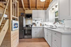 にあるPNW River Cabin - A-Frame Loft Hot tub & firepit.の白いキャビネットと木製の天井が備わるキッチン