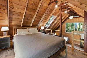 にあるPNW River Cabin - A-Frame Loft Hot tub & firepit.の木造キャビン内のベッド1台が備わるベッドルーム1室を利用します。
