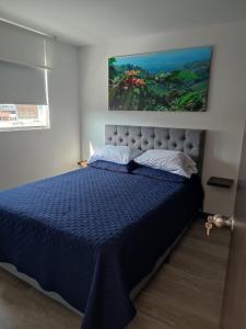 Schlafzimmer mit einem Bett mit blauer Decke in der Unterkunft Apartamento céntrico en Manizales, costo por noche $125.000 in Manizales