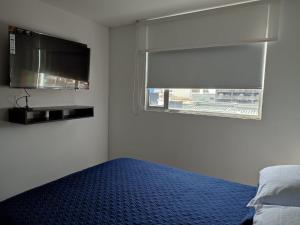 a bedroom with a bed and a window with a tv at Apartamento céntrico en Manizales, costo por noche $125.000 in Manizales