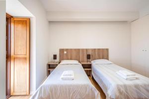 2 bedden in een witte kamer met een deur bij Casa da Eira in Tondela