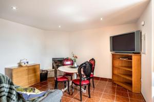 een woonkamer met een tafel en stoelen en een televisie bij Casa da Eira in Tondela