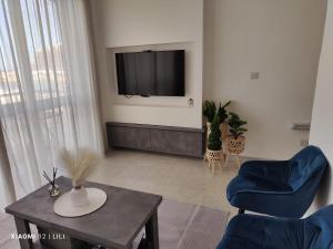 uma sala de estar com uma televisão e uma mesa e cadeiras em Lilly's Sea view, beachfront apartment em Marsalforn
