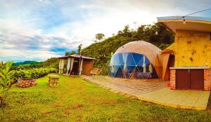 a large tent in a yard next to a house at Las Colinas Glamping in Turrialba