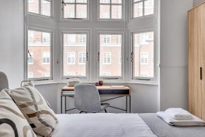 a bedroom with a bed and a desk and windows at The Abingdon in London