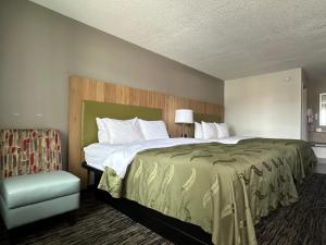 a bedroom with a large bed and a chair at Quality Inn Calhoun North I-75 in Calhoun