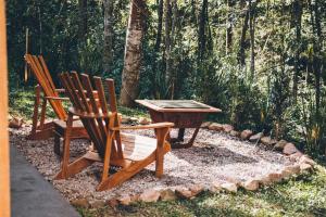 twee houten stoelen en een tafel in de tuin bij Cabana da Represa - Curitiba/PR in Curitiba