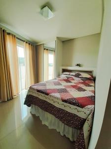 ein Schlafzimmer mit einem Bett mit einer Decke darauf in der Unterkunft Cobertura Ap praia de Bombas in Bombinhas