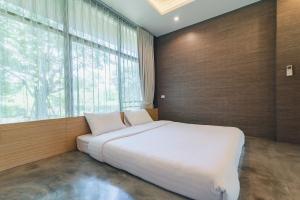 a large white bed in a room with a large window at THAN KhaoYai Pak Chong 2-7 ppl & Private Lake in Ban Khlong Yang