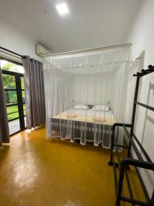 - une chambre avec un lit à baldaquin blanc dans l'établissement Pearl Villa Rooms and Hostel, à Unawatuna