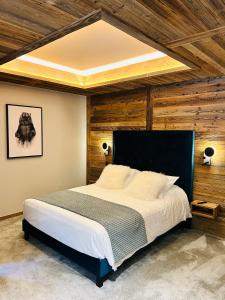 a bedroom with a large bed with wooden walls at Hameau des Prodains - Résidence in Morzine