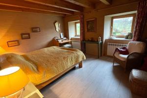 ein Schlafzimmer mit einem Bett und einem Stuhl in einem Zimmer in der Unterkunft La maison aux volets blancs in Beaux