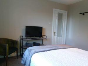 a bedroom with a bed and a flat screen tv at Dún Eoin Carrigaline in Carrigaline