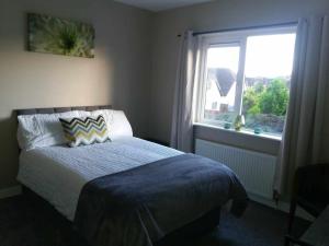 a bedroom with a bed and a window at Dún Eoin Carrigaline in Carrigaline