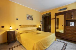 a yellow bedroom with a bed and a mirror at Agriturismo Edoardo Patrone in Domodossola