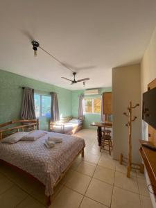 ein Schlafzimmer mit einem Bett und einem Tisch in einem Zimmer in der Unterkunft Pousada Ondas do Embaú in Palhoça