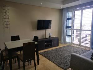 a living room with a dining table and a television at Seaside apartment - Big Bay beach in Cape Town