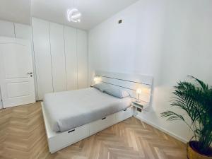 um quarto branco com uma cama e um vaso de plantas em WANDERLUST Splendido appartamento in centro em Pavia