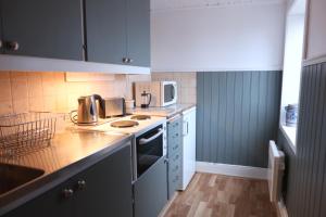 uma cozinha com armários brancos e uma bancada em Remarkable Harbour View Cabin. em Östhammar