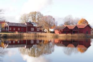 a couple of red buildings next to a body of water at Remarkable Harbour View Cabin. in Östhammar