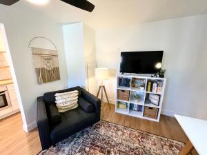 a living room with a black couch and a flat screen tv at Newly renovated, modern and cosy one bedroom condo with full kitchen and lounge in Redding