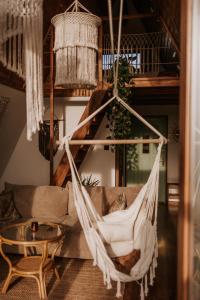 a hammock in a room with a couch and a table at Bohema in Sierpnica