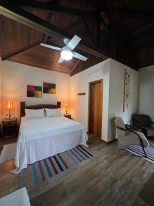 1 dormitorio con cama blanca y ventilador de techo en Pousada Cheiro da Terra, en Cunha