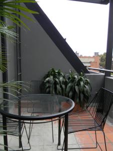 a glass table and two chairs on a balcony at Soy Local Parque La 93 in Bogotá