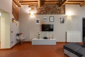 een woonkamer met een bank en een tv aan de muur bij Apartment Anfiteatro in Lucca