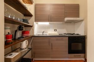 cocina con armarios de madera y horno con fogones en Apartment Anfiteatro en Lucca