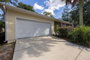 a house with a white garage with a driveway at Your UF Getaway: 1 Block from Campus - 4 BD Haven in Gainesville