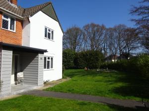 een tuin naast een wit huis met een gazon bij The Wendy House in Bournemouth
