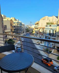 een balkon met een tafel en uitzicht op een straat bij Central Apartment, Is-Swieqi in Is-Swieqi